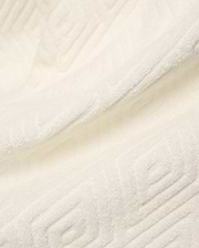 Creamy white Mens Tristan Short crafted from plush, absorbent terry cloth, featuring an intricate, subtly embossed geometric square and spiral pattern throughout the luxurious fabric.