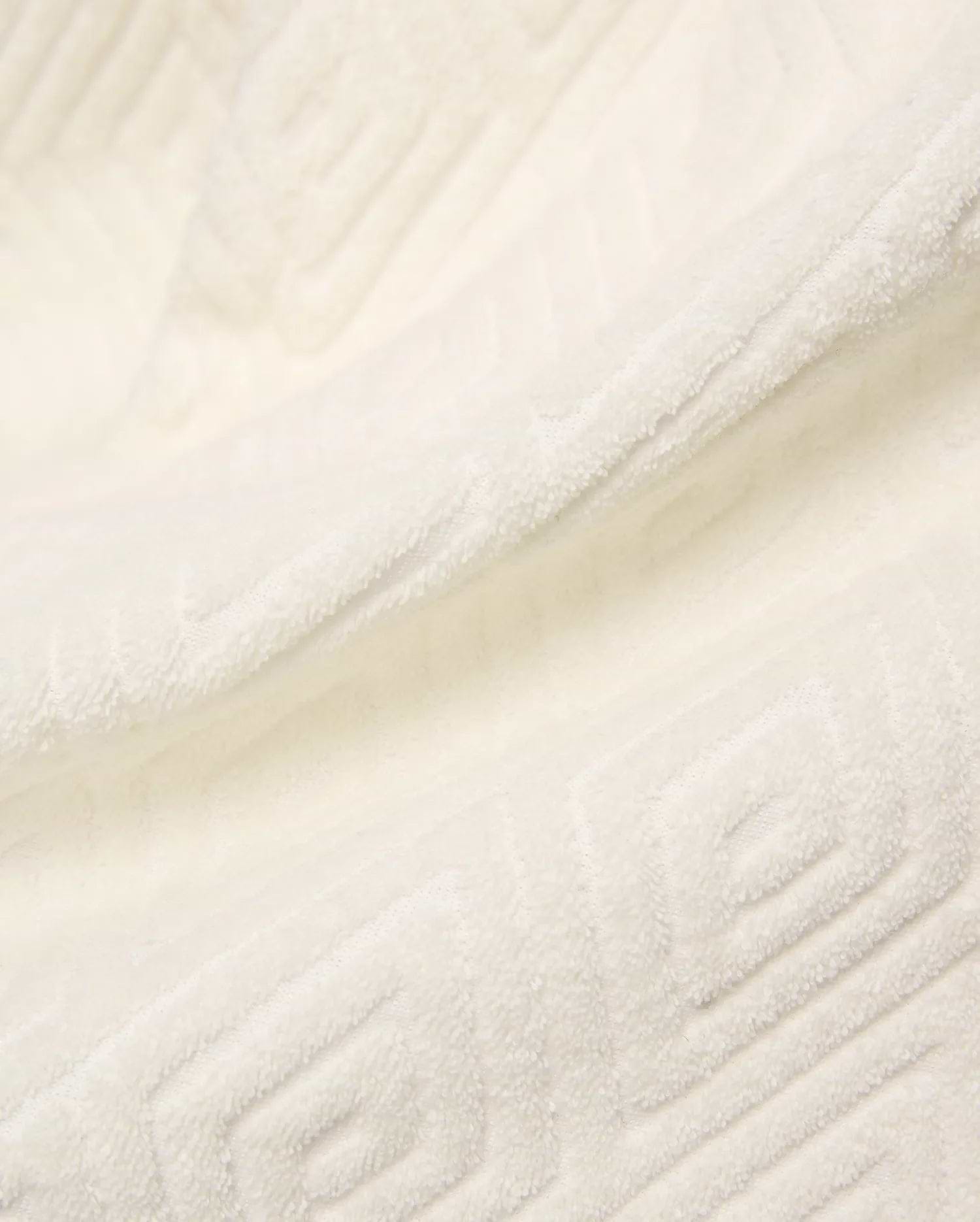 Creamy white Mens Tristan Short crafted from plush, absorbent terry cloth, featuring an intricate, subtly embossed geometric square and spiral pattern throughout the luxurious fabric.