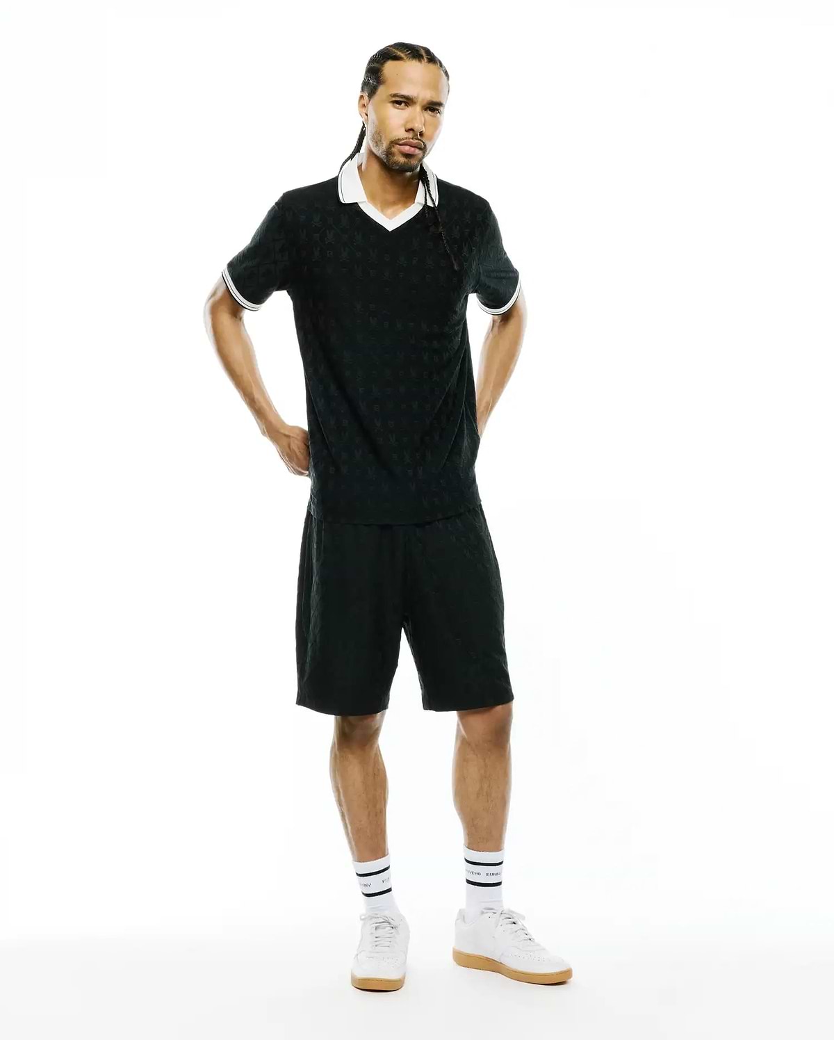 Black polo shirt and MENS GARRY JACQUARD SWEATSHORT set featuring a subtle all-over Psycho Bunny skull jacquard pattern, white V-neck collar, and white striped cuffs. Classic fit.