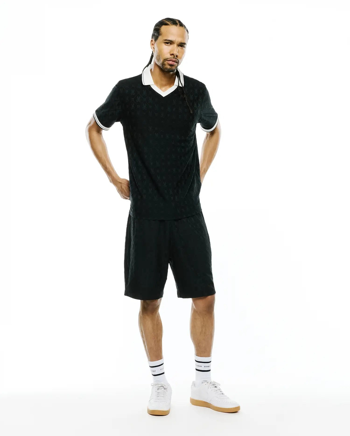 Black polo shirt and MENS GARRY JACQUARD SWEATSHORT set featuring a subtle all-over Psycho Bunny skull jacquard pattern, white V-neck collar, and white striped cuffs. Classic fit.