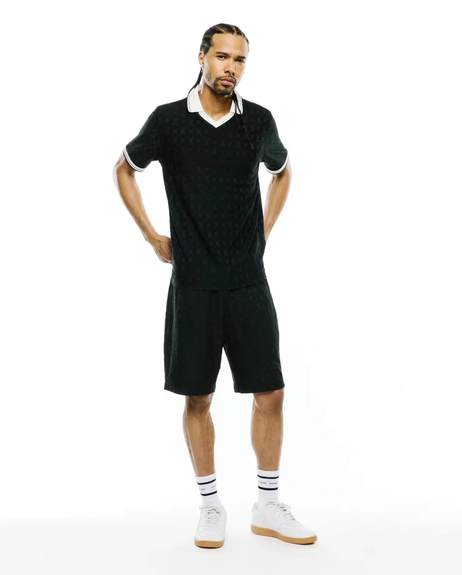 Black polo shirt and MENS GARRY JACQUARD SWEATSHORT set featuring a subtle all-over Psycho Bunny skull jacquard pattern, white V-neck collar, and white striped cuffs. Classic fit.