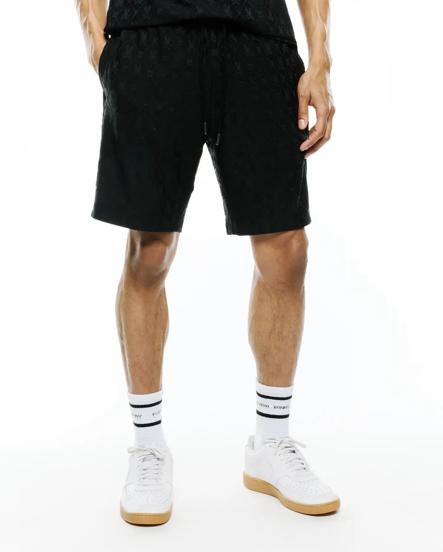 Mens Garry Jacquard Sweatshort, a black relaxed-fit short featuring a subtle tonal all-over jacquard knit Psycho Bunny skull logo pattern and an adjustable drawstring waist.