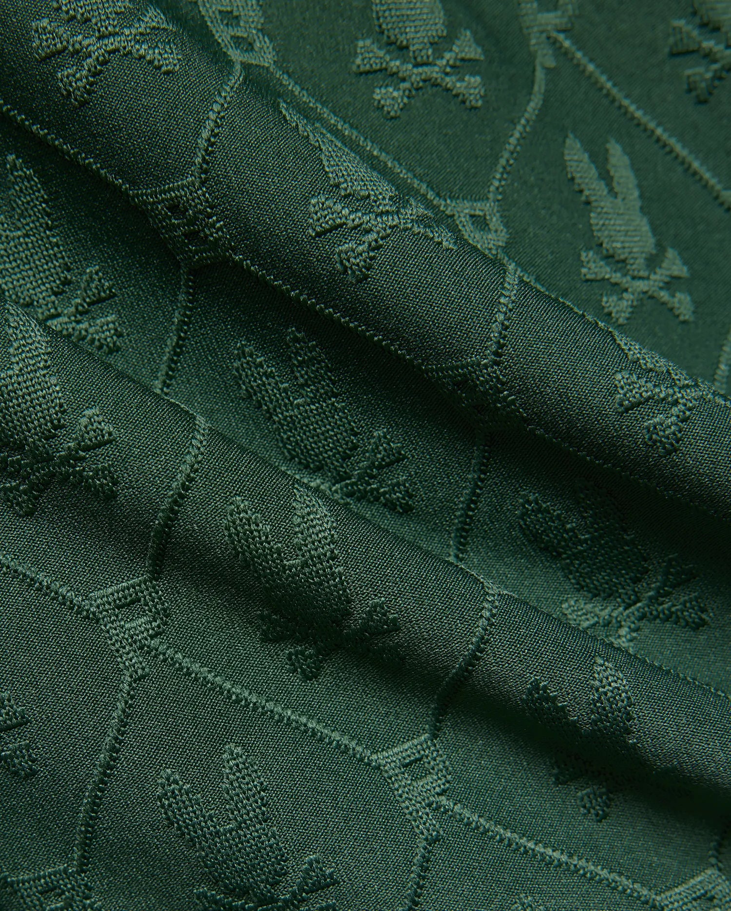 Mens Garry Jacquard Sweatshort in deep forest green, featuring a subtle all-over jacquard knit pattern of the iconic Psycho Bunny skull logo, creating a rich, textured fabric.