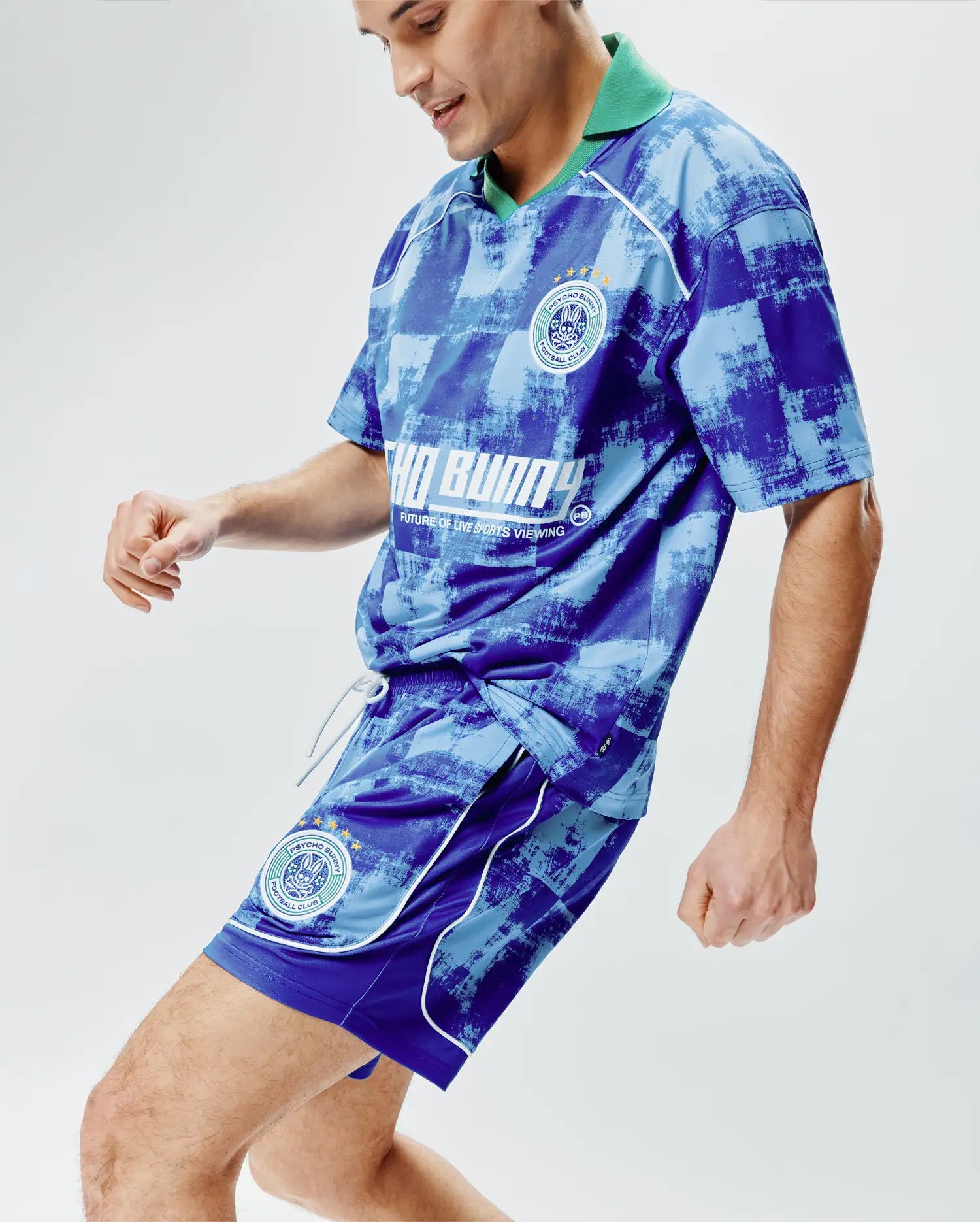 Blue and light blue checkered Psycho Bunny polo shirt and Mens Micah Soccer Short 6 3/4 set with green collar, white piping, chest and thigh Psycho Bunny Football Club crests, and large front text graphic. (2)