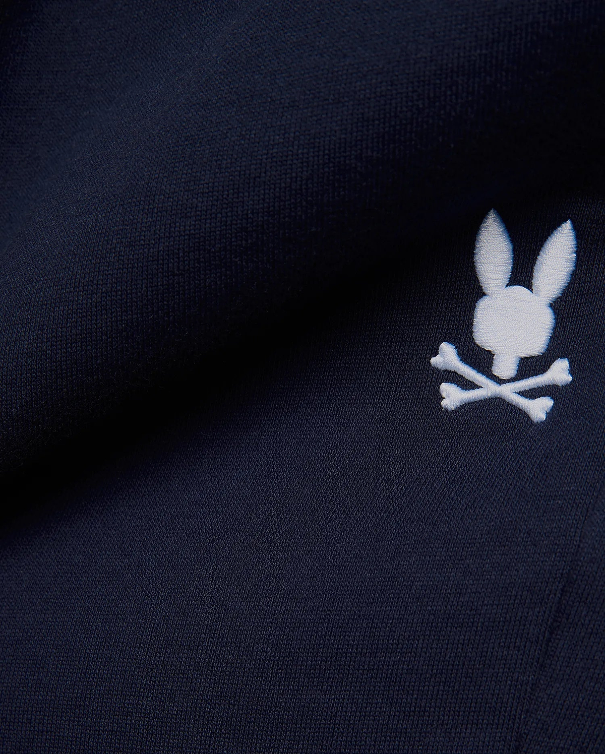 Premium deep navy blue MENS GABE FRENCH TERRY SWEATSHORT, showcasing a soft French terry knit texture and an iconic, crisp white embroidered Psycho Bunny skull logo, embodying refined streetwear style. (7)