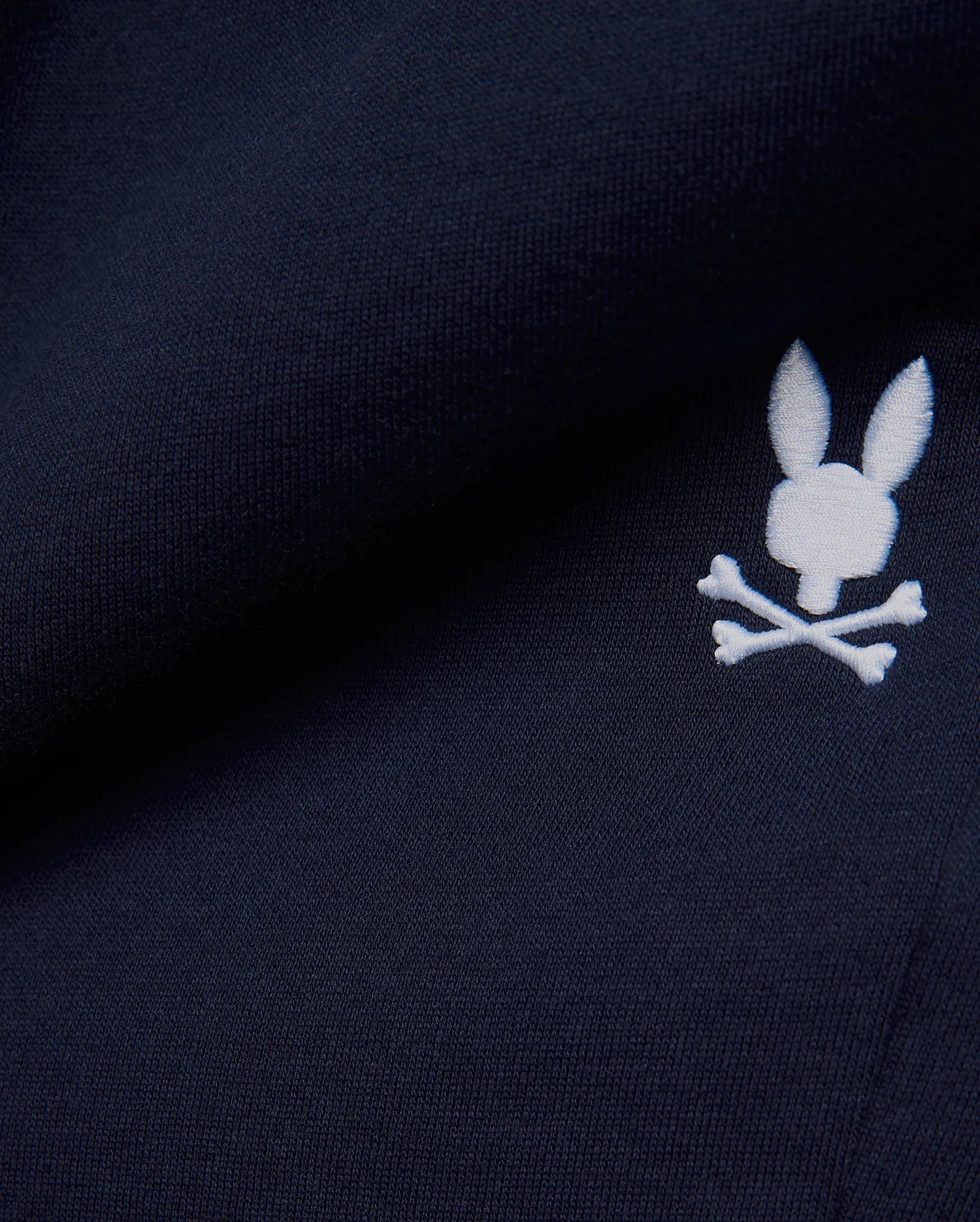 Premium deep navy blue MENS GABE FRENCH TERRY SWEATSHORT, showcasing a soft French terry knit texture and an iconic, crisp white embroidered Psycho Bunny skull logo, embodying refined streetwear style. (7)