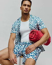 Mens Josh Swim Trunk and matching short-sleeve shirt in white with a teal pixelated pattern featuring small Psycho Bunny skull logos, a relaxed fit resort wear set.