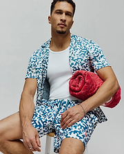 Mens Josh Swim Trunk and matching short-sleeve shirt in white with a teal pixelated pattern featuring small Psycho Bunny skull logos, a relaxed fit resort wear set.