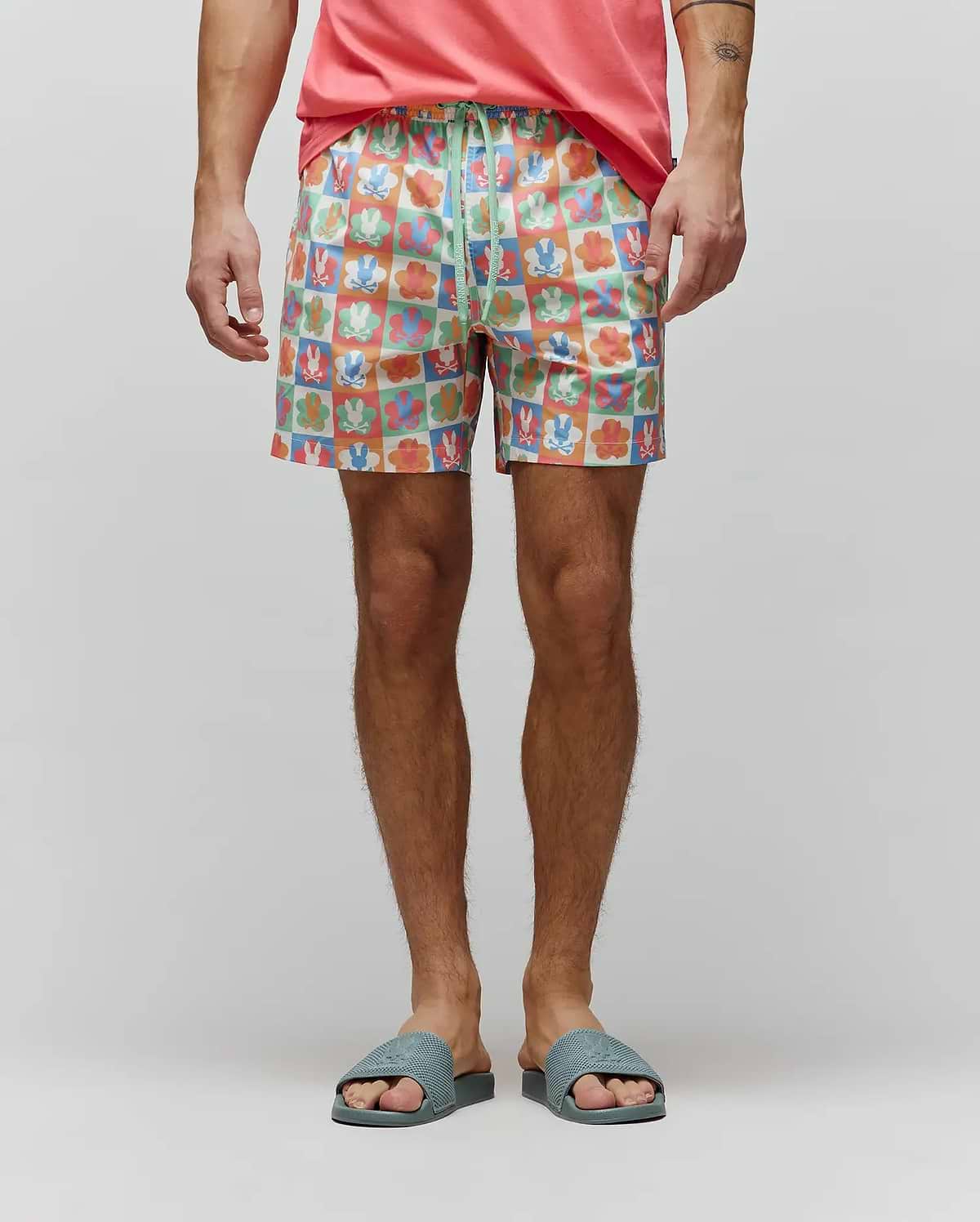 Mens Aiden Swim Trunk in a vibrant multi-color checkered print featuring Psycho Bunny skull logos and flower graphics, with a green drawstring displaying the brand name. Relaxed fit, smooth fabric. (1)