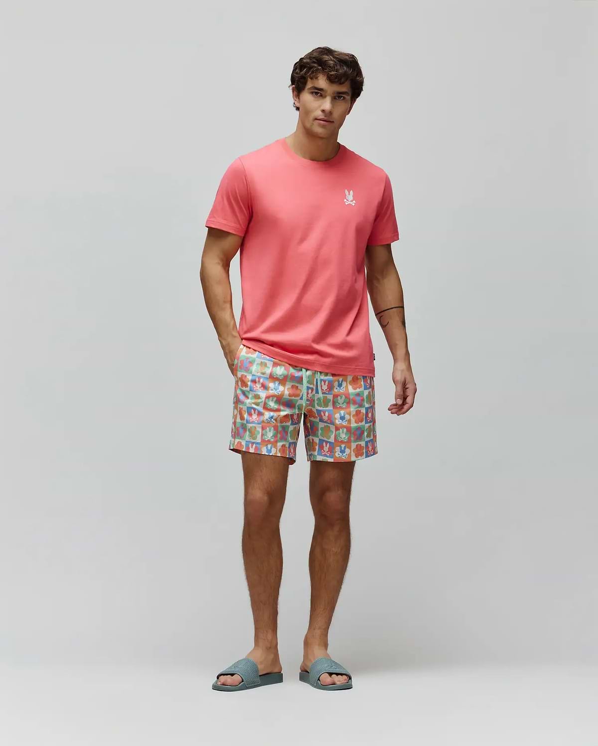 Coral pink classic fit jersey t-shirt with small white embroidered Psycho Bunny logo on left chest, paired with Mens Aiden Swim Trunk featuring a vibrant multi-color checkerboard pattern of Psycho Bunny skull logos and a drawstring waist. (4)
