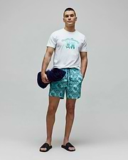 White classic fit jersey t-shirt with a large gradient blue Psycho Bunny text and bunny skull chest graphic. Mens Luke Swim Trunk in teal features an all-over dark blue bandana print with integrated bunny skull logos.