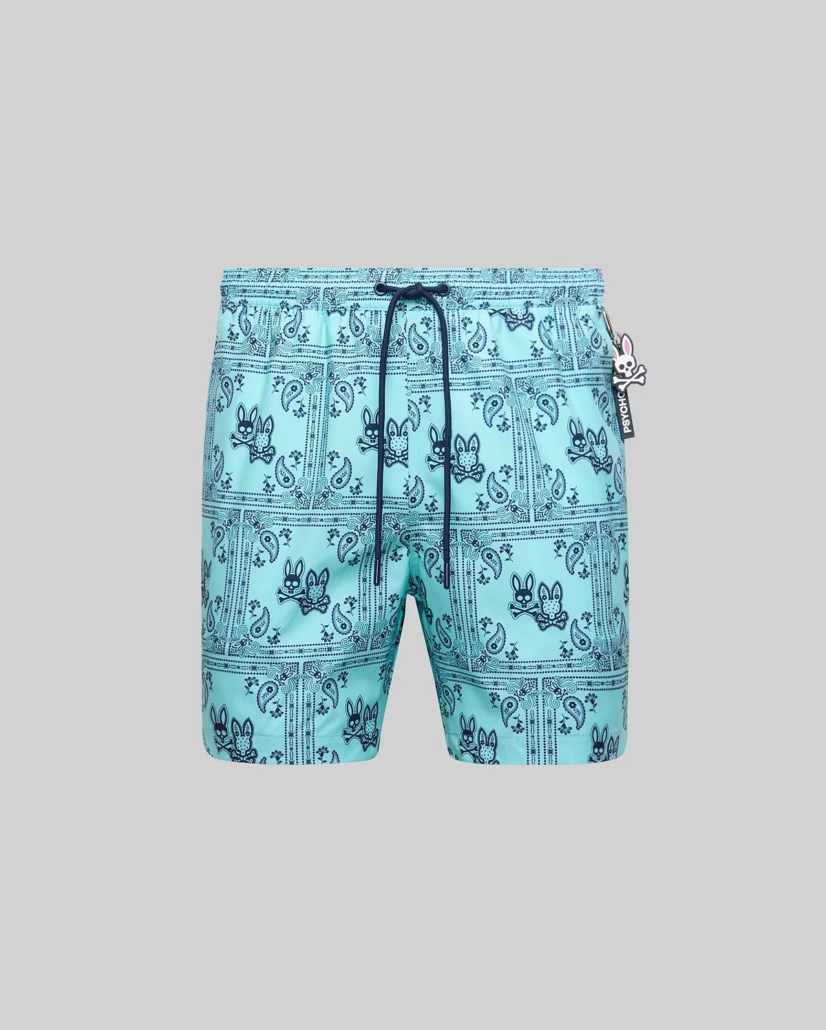 Mens Luke Swim Trunk in aqua, featuring a dark blue all-over bandana paisley print with integrated Psycho Bunny skull logos, classic fit, smooth quick-dry fabric, and a small Psycho Bunny logo tag.