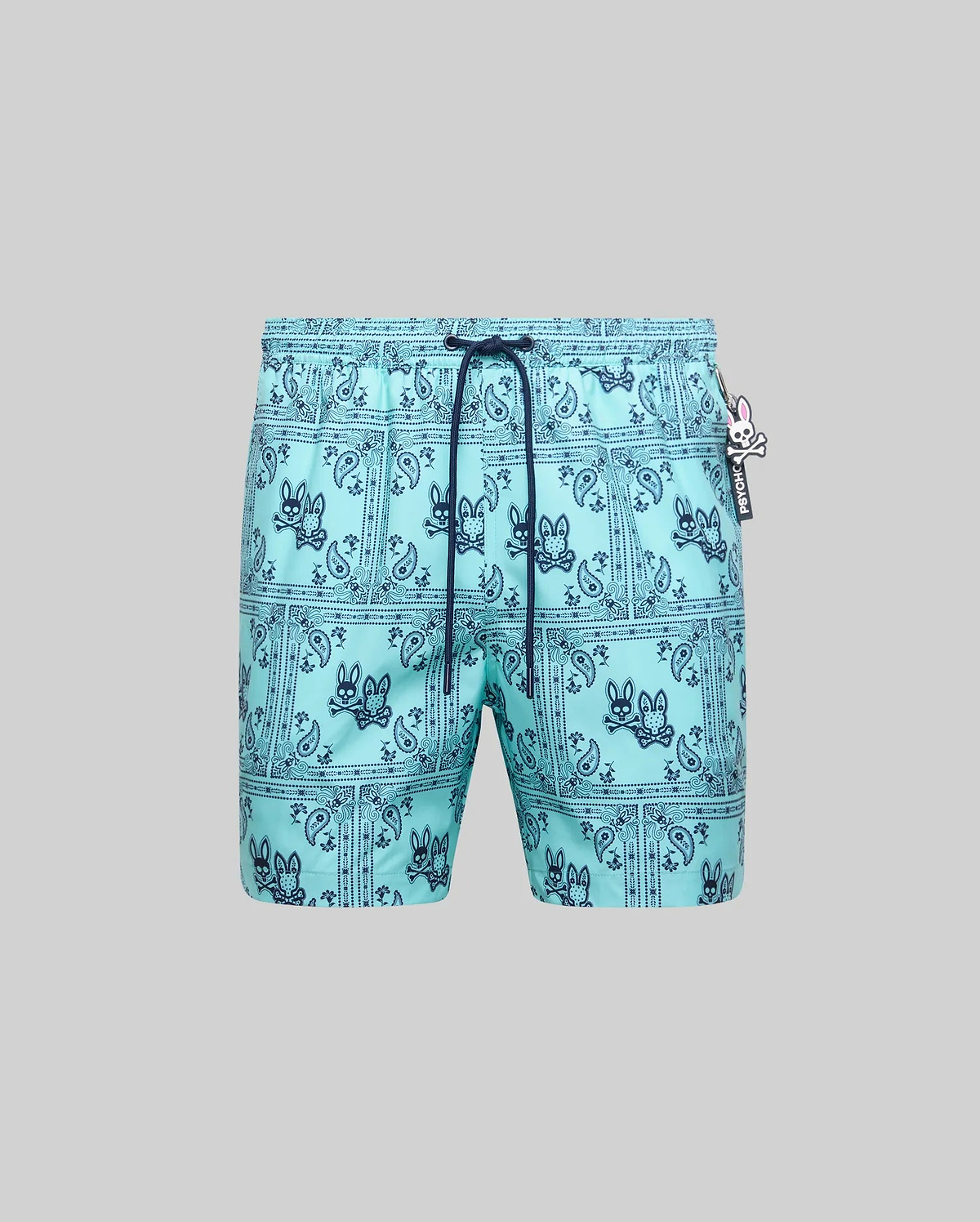 Mens Luke Swim Trunk in aqua, featuring a dark blue all-over bandana paisley print with integrated Psycho Bunny skull logos, classic fit, smooth quick-dry fabric, and a small Psycho Bunny logo tag.