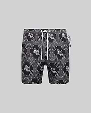 Mens Luke Swim Trunk in black with an all-over white bandana paisley print featuring the iconic Psycho Bunny skull logo, complete with a white drawstring and small Psycho Bunny tag, offering a classic fit in smooth, quick-dry fabric.