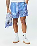 Mens Brad Swim Trunk in blue with white vertical stripes, transitioning to a scalloped pattern featuring palm trees and small Psycho Bunny skull logos. Relaxed fit, smooth fabric.