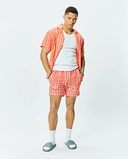 Coral striped short-sleeve button-up shirt with sleeve logo, white crew neck t-shirt, and Mens Brad Swim Trunk featuring matching stripes, palm tree, and bunny skull pattern with Psycho Bunny drawstring.
