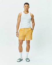 Mens Brad Swim Trunk, vibrant yellow with white vertical stripes on top, transitioning to an all-over Psycho Bunny skull logo pattern on the bottom, featuring a relaxed fit, smooth quick-dry fabric, and a white drawstring waist.