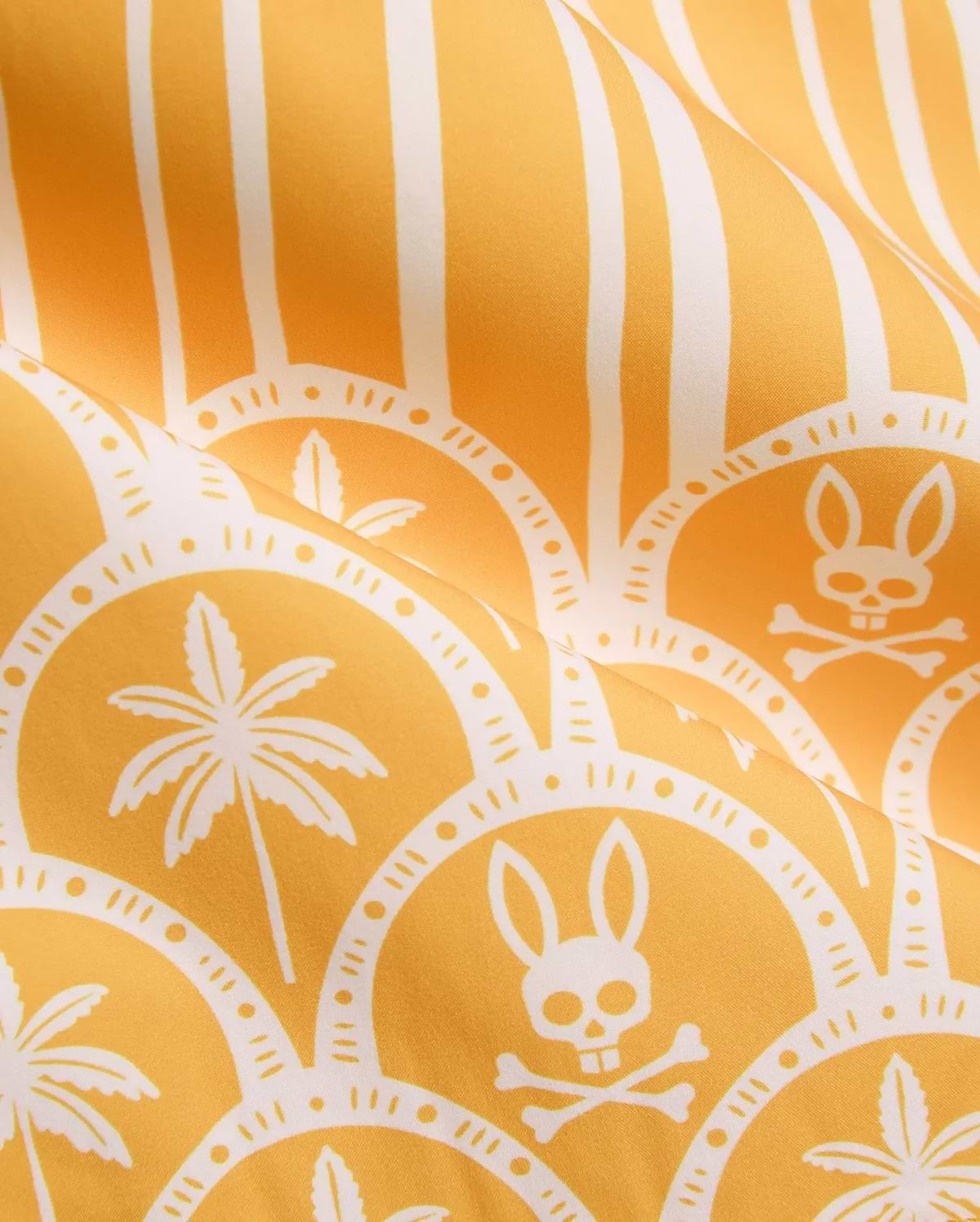 Vibrant yellow Mens Brad Swim Trunk with white vertical stripes, scalloped pattern, palm tree graphics, and repeated Psycho Bunny skull and crossbones logos on smooth quick-dry fabric.