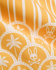 Vibrant yellow Mens Brad Swim Trunk with white vertical stripes, scalloped pattern, palm tree graphics, and repeated Psycho Bunny skull and crossbones logos on smooth quick-dry fabric.