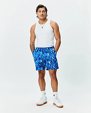 Mens Tanner Swim Trunk, a relaxed fit blue swim trunk featuring an all-over camouflage print composed of repeating Psycho Bunny skull logos, with a drawstring waist and a small brand tag.