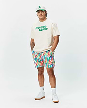 Relaxed fit cream jersey t-shirt with bold green PSYCHO BUNNY chest graphic, vibrant multi-color abstract floral Mens Tanner Swim Trunk, white cap with green bunny skull logo, and white logo socks. (4)