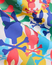 Mens Tanner Swim Trunk with a vibrant all-over print on white smooth woven fabric, featuring overlapping blue, red, yellow, green, and light blue Psycho Bunny skull and crossbones logos. (6)