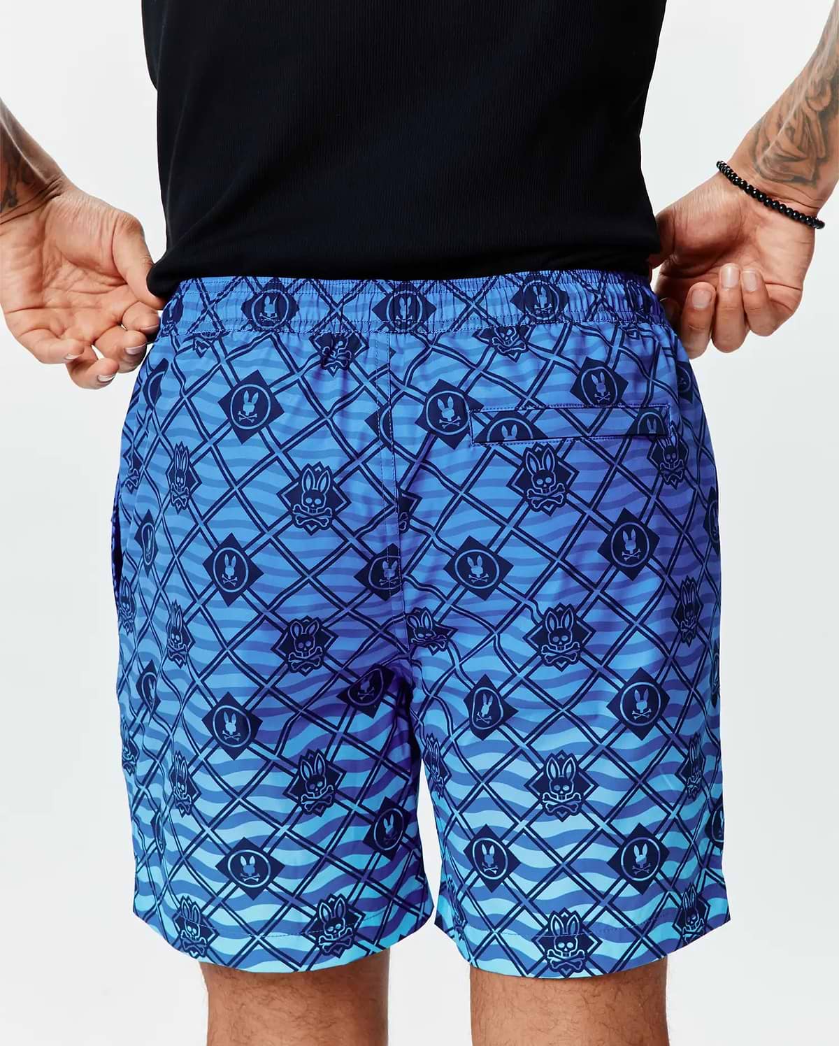 Mens Tobias Gradient Swim Trunk in a blue gradient with an all-over dark blue Psycho Bunny skull logo and diagonal grid pattern over a wavy background on smooth, relaxed-fit quick-dry fabric. (3)