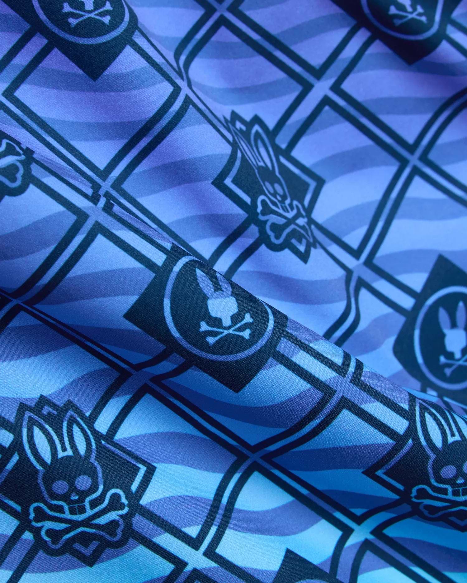 Mens Tobias Gradient Swim Trunk in a blue and purple gradient, featuring an all-over geometric grid pattern with repeated Psycho Bunny skull logos on smooth woven fabric. (6)