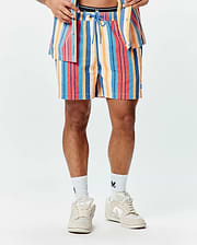 Mens Hubert Swim Trunk, a multi-colored striped swim trunk with blue, red, orange, and cream vertical stripes, featuring a textured fabric, blue drawstring, and a small embroidered Psycho Bunny skull logo on the left leg.