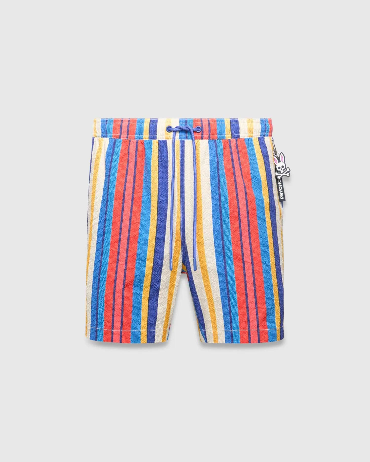Mens Hubert Swim Trunk featuring vibrant multi-color vertical stripes in cream, blue, red, and yellow, with a textured fabric, royal blue drawstring, and a small Psycho Bunny skull logo charm on the right side.