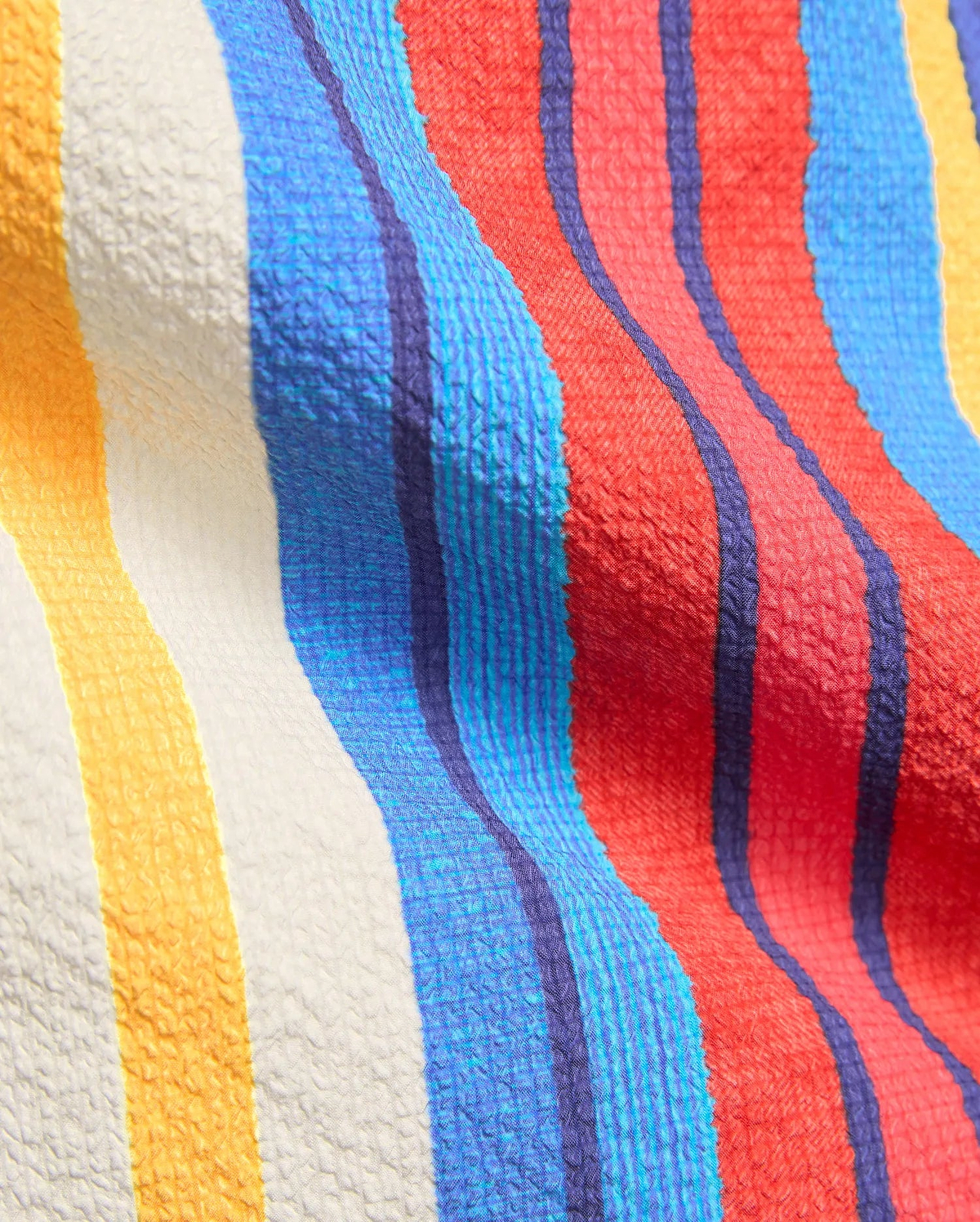 Mens Hubert Swim Trunk with vibrant vertical stripes in red, royal blue, light blue, white, and golden yellow, showcasing a unique textured seersucker-like fabric.