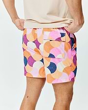 Mens Ethan Swim Trunk 6, a vibrant, relaxed-fit swim trunk with smooth fabric. It features a bold mosaic-style circular pattern in pink, orange, purple, navy, and cream, with side and back flap pockets. (2)
