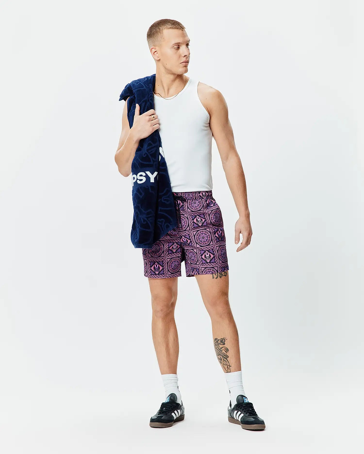 Mens Frank Swim Trunk 6, a vibrant purple and lilac all-over geometric pattern with integrated Psycho Bunny skull logos, featuring a relaxed fit and black drawstring.