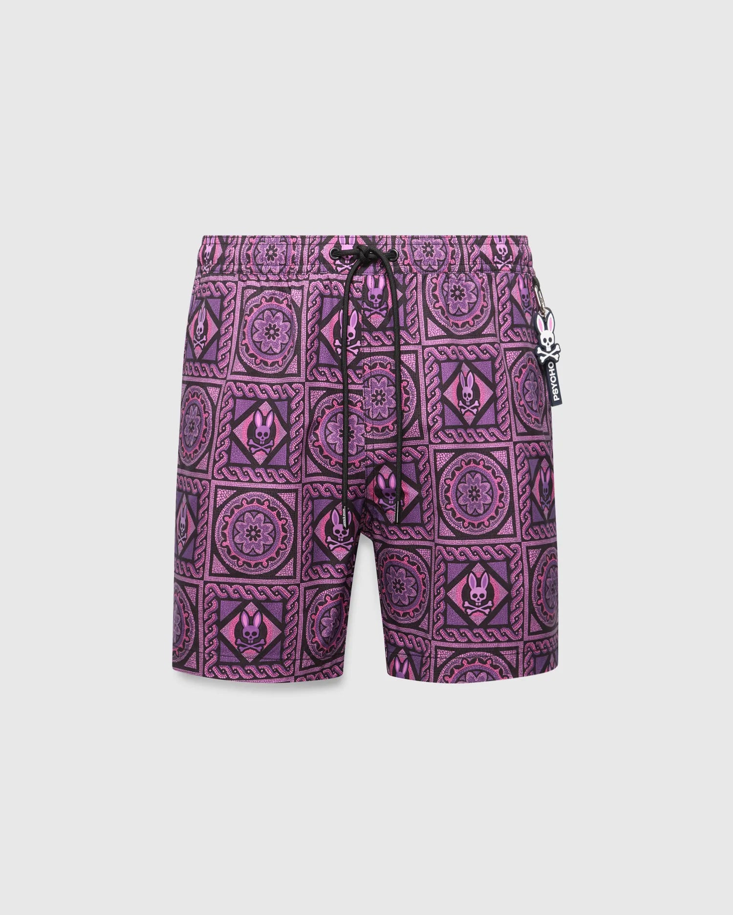 Mens Frank Swim Trunk 6, a vibrant purple and black mosaic pattern swim trunk with repeated Psycho Bunny skull and floral motifs, classic fit, and a Psycho Bunny charm on the black drawstring.