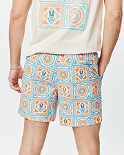 Mens Frank Swim Trunk 6, a classic fit, white swim trunk with a vibrant blue and orange mosaic tile pattern, featuring the iconic Psycho Bunny skull logo integrated throughout the print. Smooth fabric.