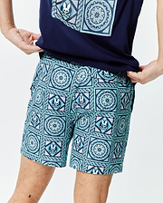 Mens Frank Swim Trunk 6, a classic fit swim trunk in a vibrant blue and teal mosaic pattern, intricately featuring the iconic Psycho Bunny skull logo and floral designs throughout the smooth fabric.