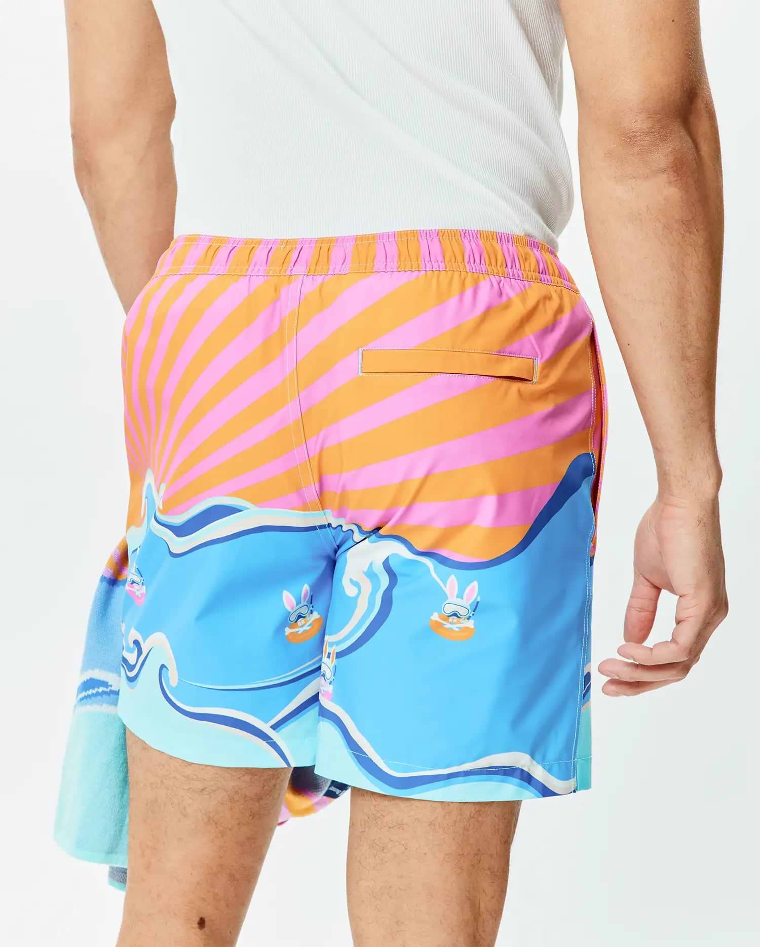 Mens Ray Swim Trunk 6 featuring a vibrant pink and orange striped sunburst pattern, light blue waves, and playful Psycho Bunny characters wearing snorkels. (3)