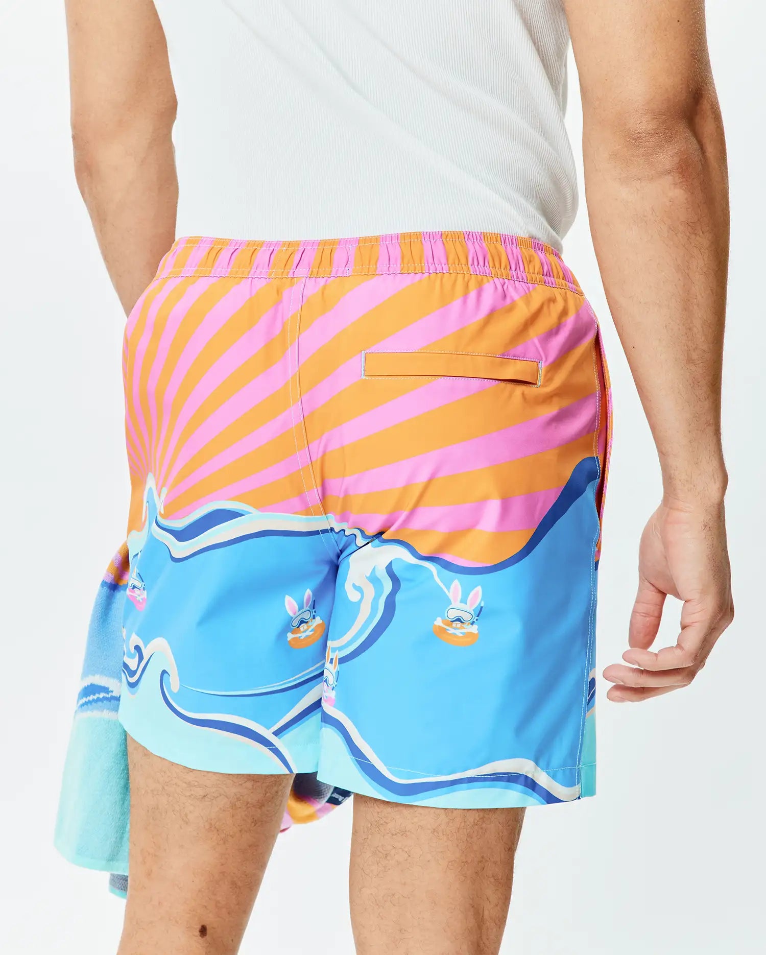 Mens Ray Swim Trunk 6 featuring a vibrant pink and orange striped sunburst pattern, light blue waves, and playful Psycho Bunny characters wearing snorkels. (3)