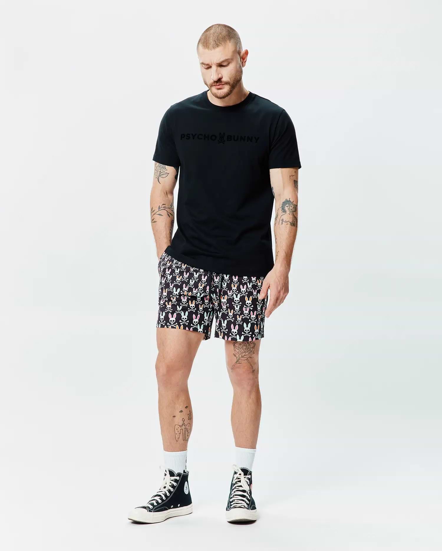 Black classic fit jersey t-shirt with tonal Psycho Bunny chest logo, paired with Mens Byron Swim Trunk 6 featuring an all-over colorful bunny skull print on black fabric. (4)