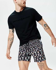 Black jersey t-shirt with a tone-on-tone Psycho Bunny text and skull chest logo, paired with Mens Byron Swim Trunk 6 featuring an all-over multicolor bunny skull and crossbones print. (3)