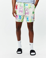 Mens Quintin All Over Print Swim Trunk, a classic fit cream swim trunk with vibrant multi-color Psycho Bunny skull logo and paint splatter all-over print, featuring a neon green drawstring with Psycho Bunny text.