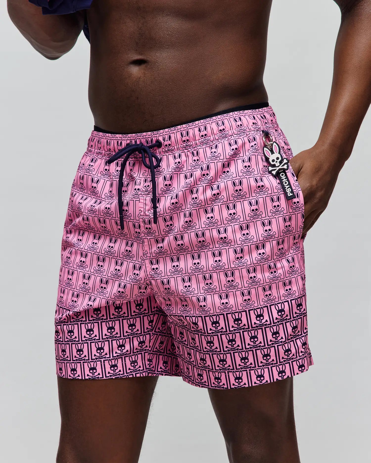 Mens Keon Swim Trunk, vibrant pink with a classic fit and smooth quick-dry fabric. Features an all-over navy grid print of Psycho Bunny heads and skull & crossbones, navy drawstring, and a small side logo tag. (2)