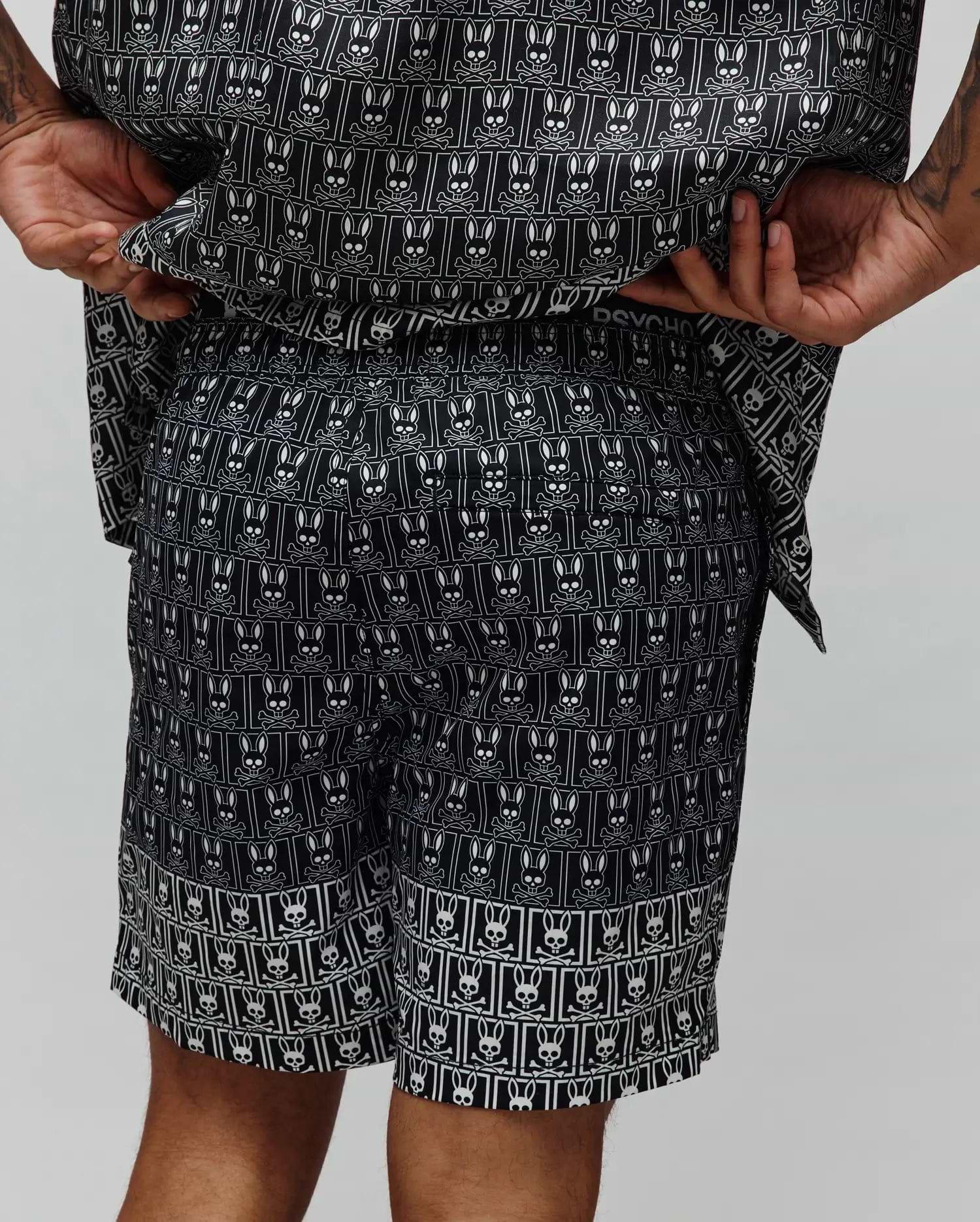 Mens Keon All Over Bunny Swim Trunk, black with an iconic white Psycho Bunny skull logo pattern repeated in rectangular frames, featuring a relaxed fit and smooth, quick-dry fabric.