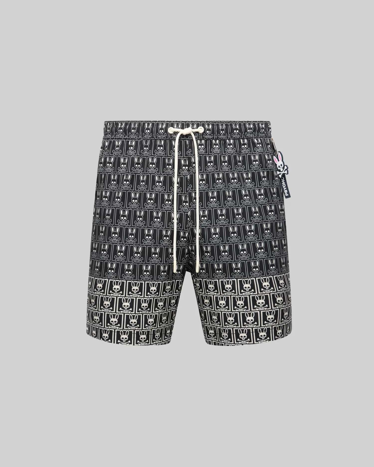 Mens Keon All Over Bunny Swim Trunk: Black classic fit swim trunk featuring an all-over white bunny skull logo pattern, white drawstring, and a small pink and white Psycho Bunny tag on the right side.