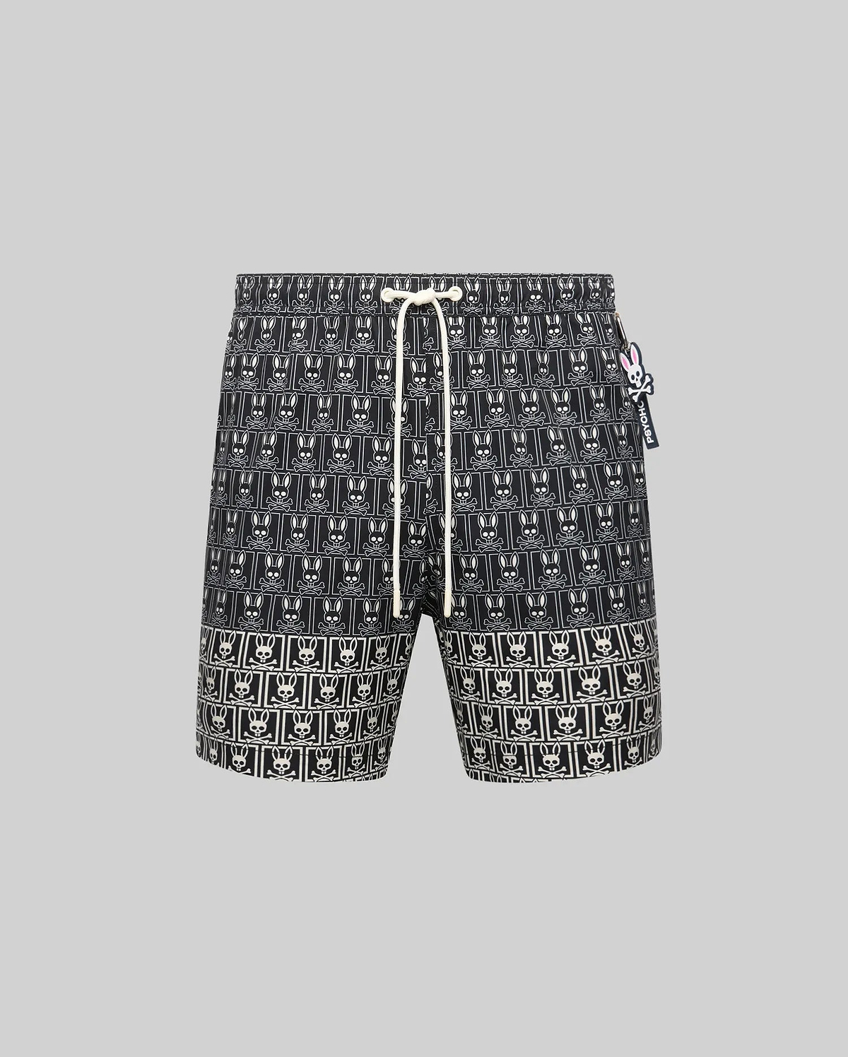 Mens Keon All Over Bunny Swim Trunk: Black classic fit swim trunk featuring an all-over white bunny skull logo pattern, white drawstring, and a small pink and white Psycho Bunny tag on the right side.