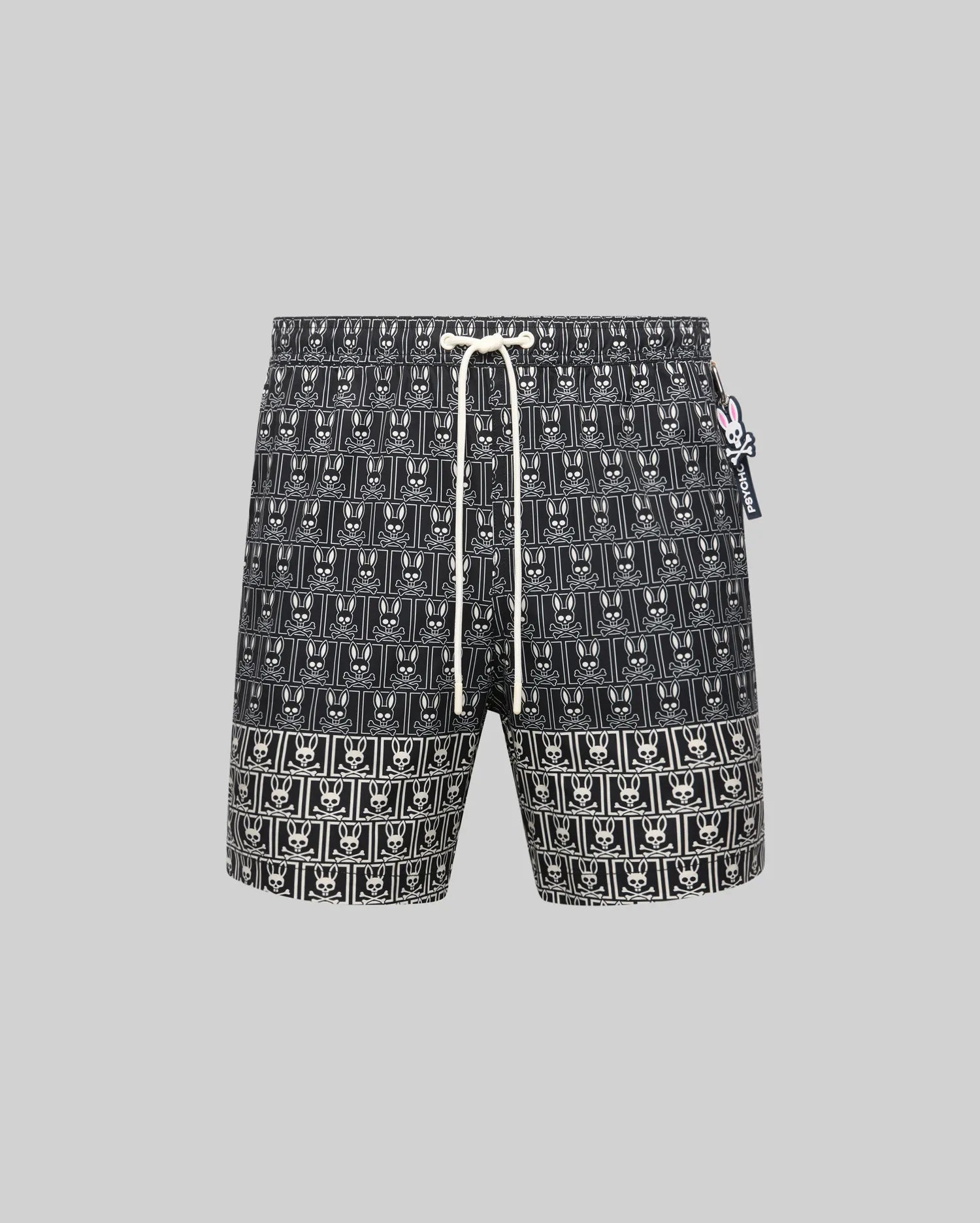 Mens Keon All Over Bunny Swim Trunk: Black classic fit swim trunk featuring an all-over white bunny skull logo pattern, white drawstring, and a small pink and white Psycho Bunny tag on the right side.