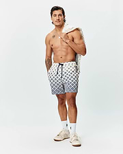 Mens Tobias Swim Trunk in cream with a navy blue geometric pattern, featuring a navy drawstring, small Psycho Bunny skull logo on the left leg, and a branded side tag.