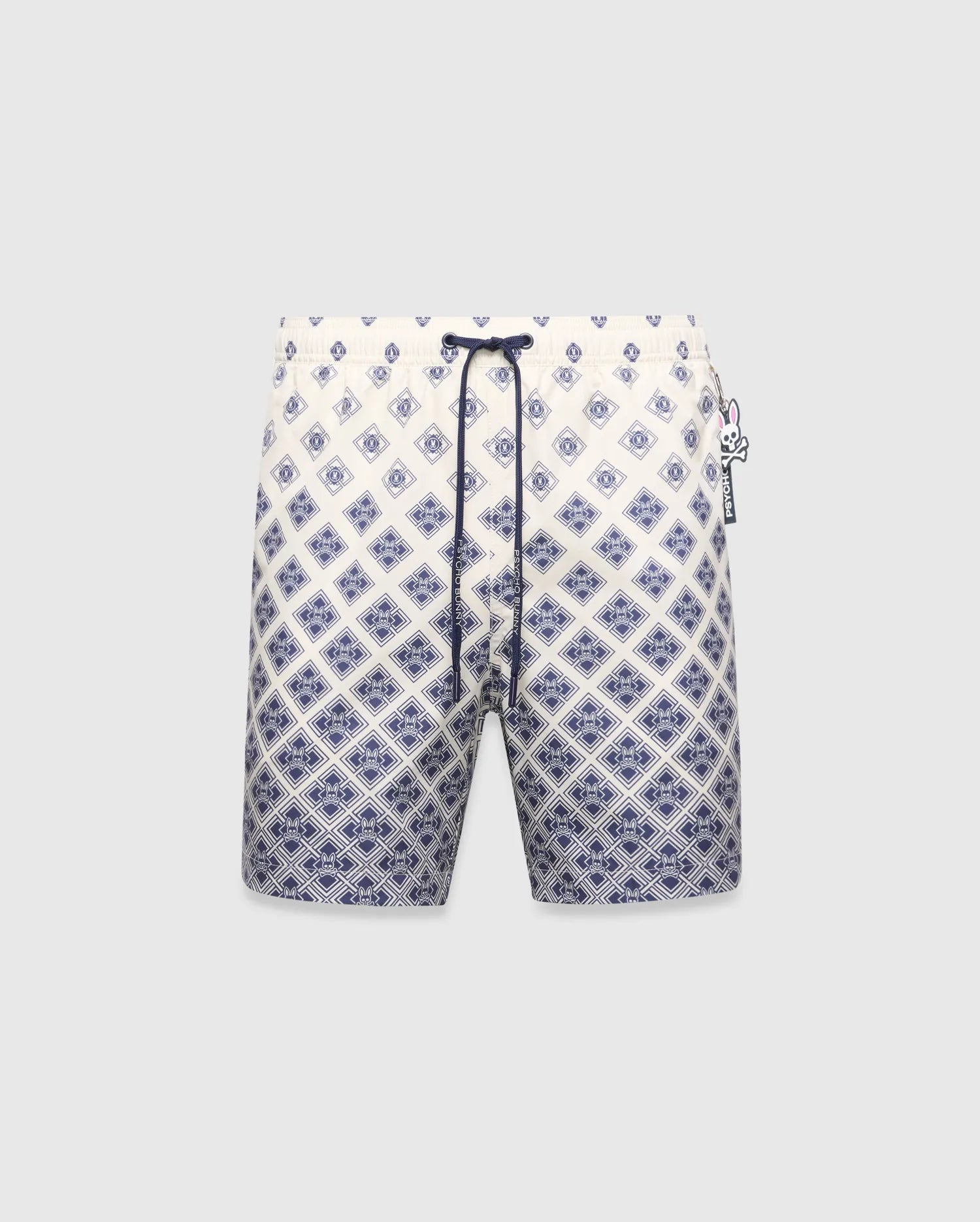 Mens Tobias Swim Trunk, cream with a navy blue gradient geometric pattern subtly integrating the Psycho Bunny skull logo, featuring a navy drawstring and logo zipper pull.