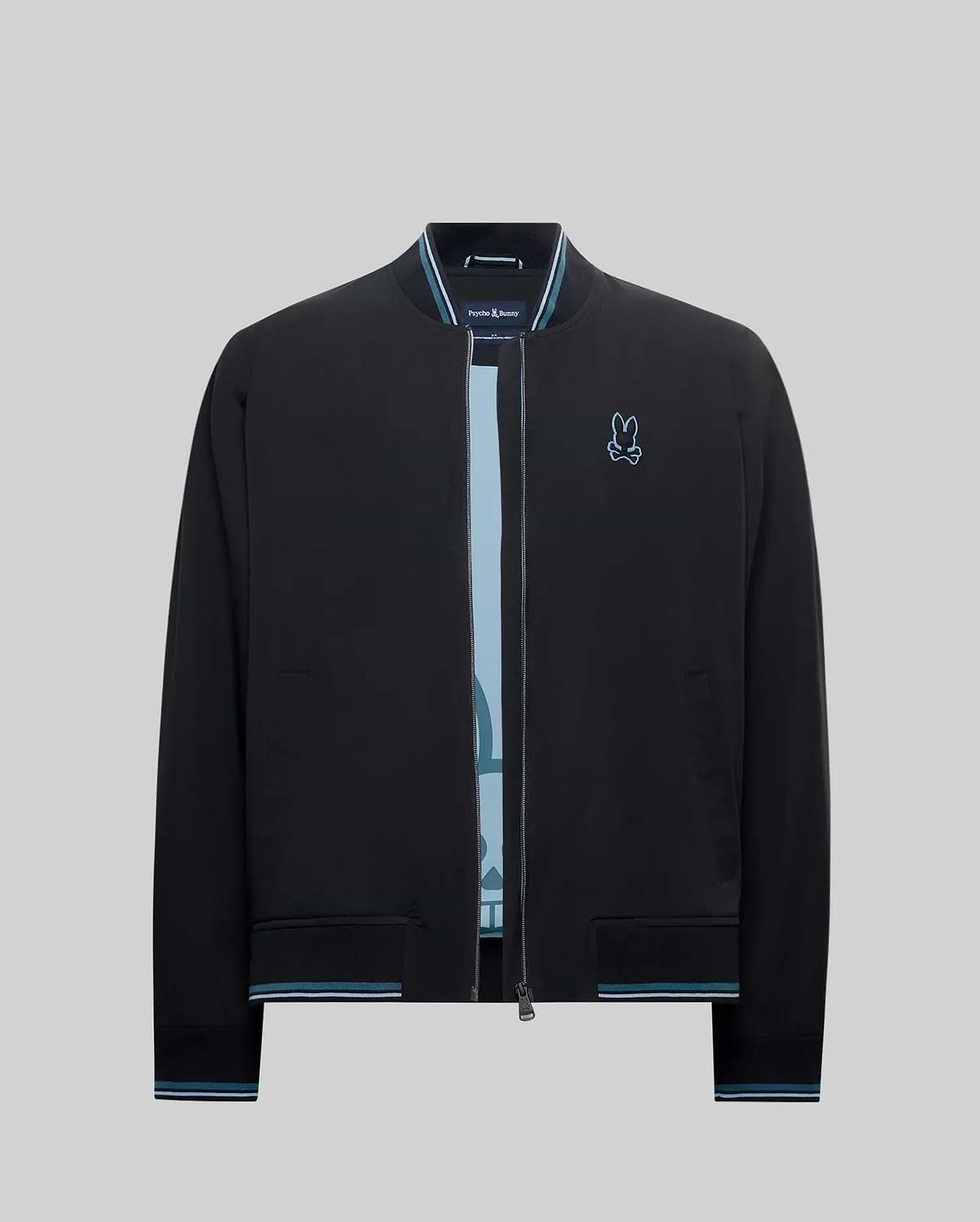Mens Aldrin Bomber, a black classic fit jacket with light blue striped ribbed collar, cuffs, and hem, featuring an embroidered light blue Psycho Bunny skull logo on the left chest. (7)