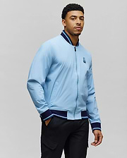Mens Aldrin Bomber in light blue with navy and light blue striped ribbed collar, cuffs, and hem, featuring a full zip front and an embroidered Psycho Bunny skull logo on the left chest, classic fit. (5)